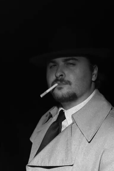 Alfred Noseworth in trench coat and fedora